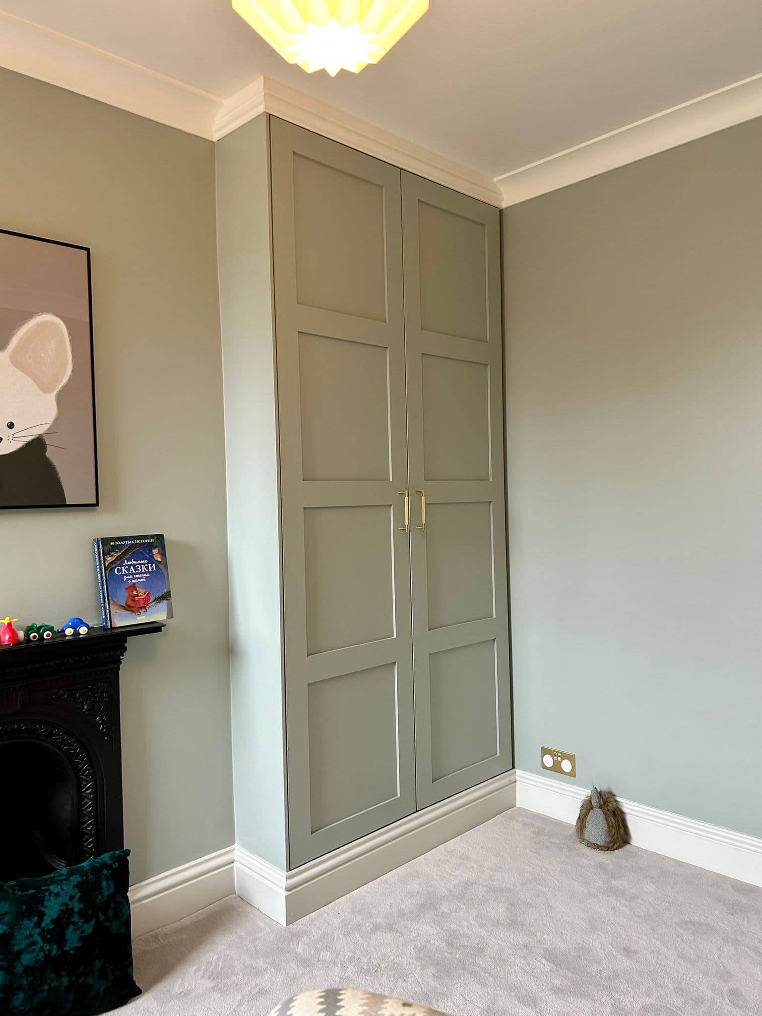 Floor-to-ceiling fitted wardrobe with paneled doors in sage green