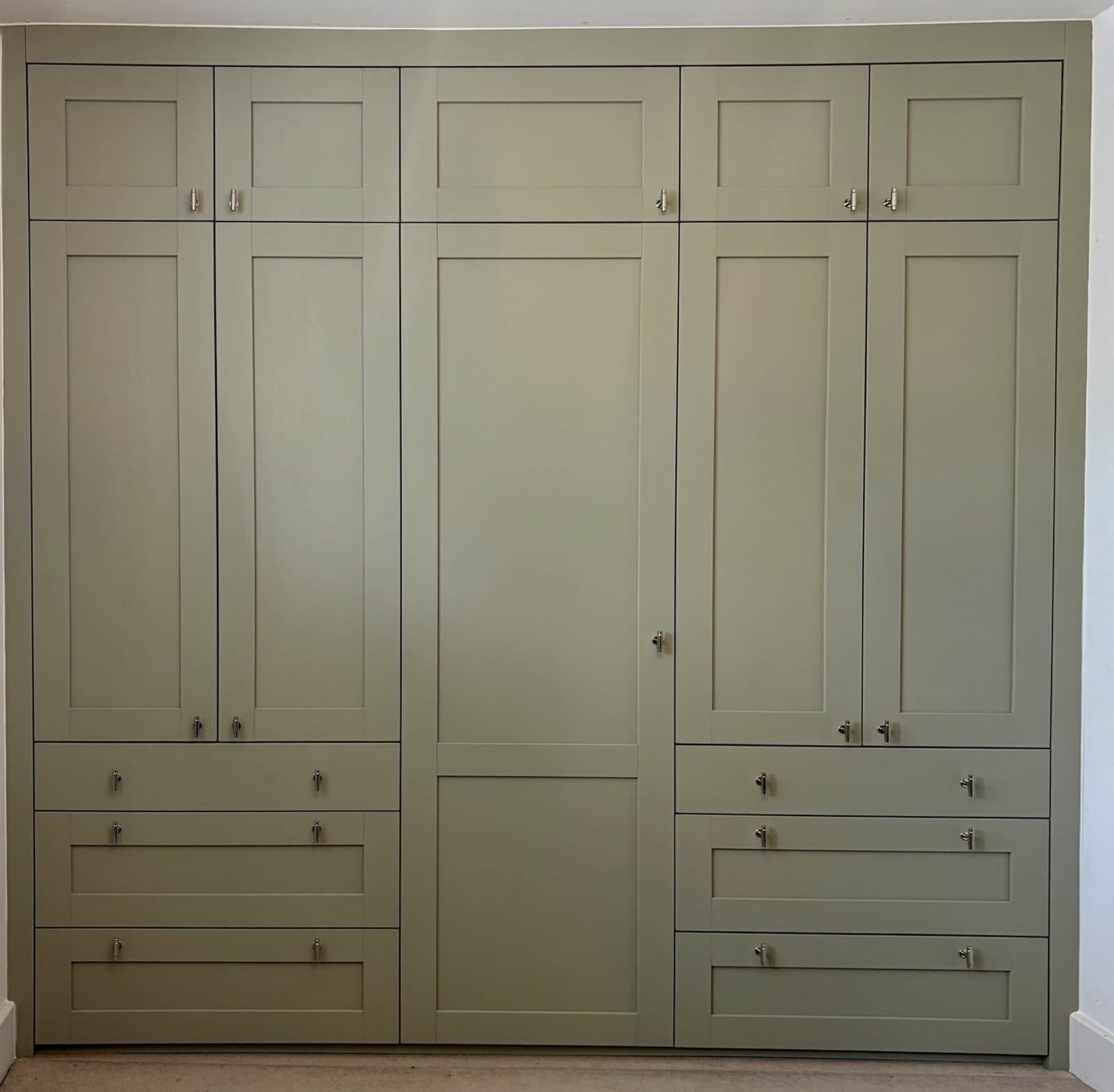 Green hand-painted fitted wardrobes built to the full height and width of the room